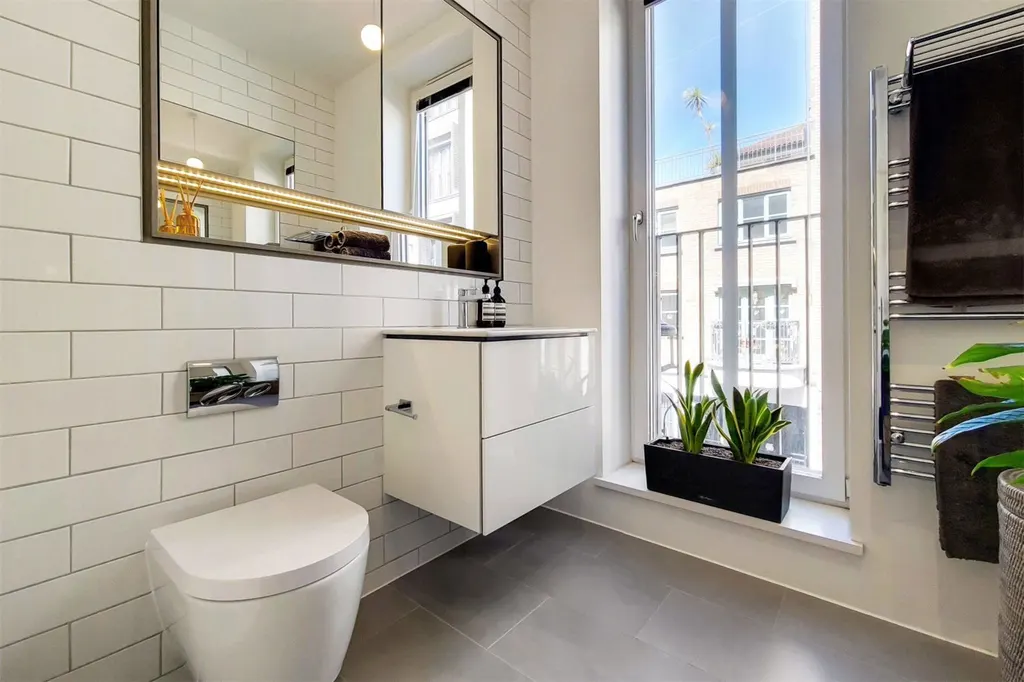 Bathroom with white metro tiles, wall-hung basin, mirror and heated towel rail