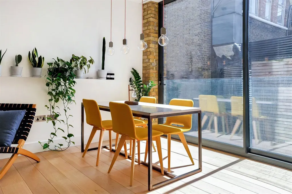 Dining area with plants beside floor-to-ceiling glazing