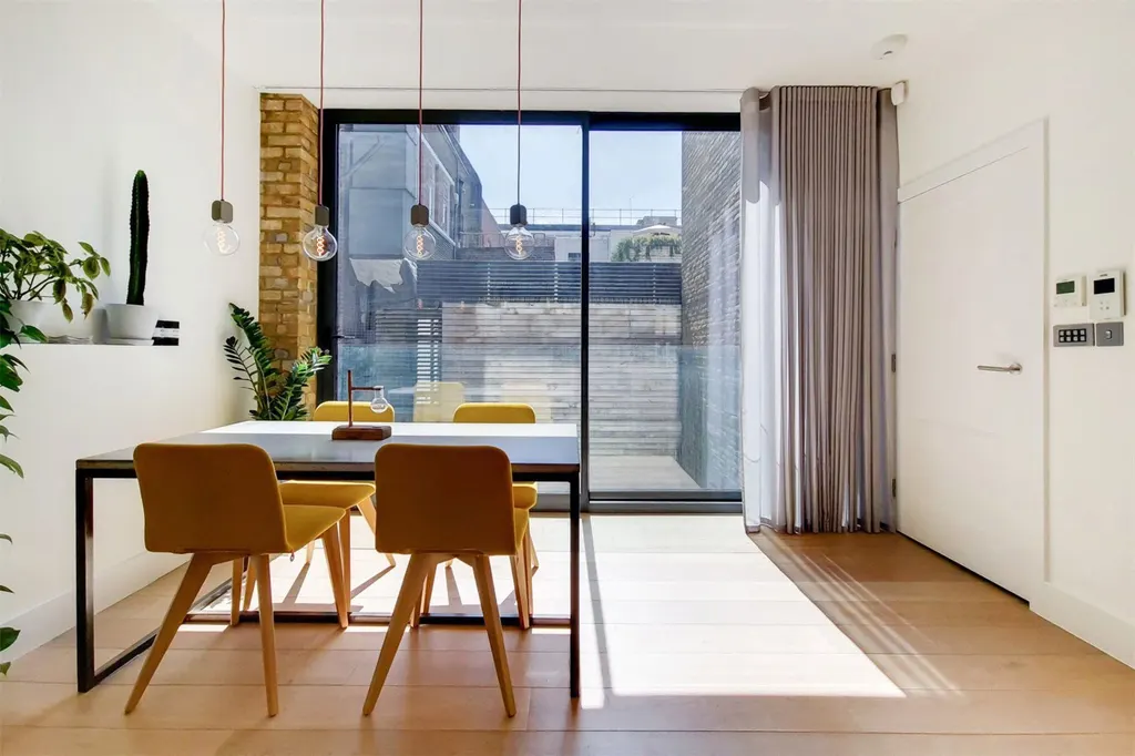 Dining table with pendant lights beside floor-to-ceiling sliding doors
